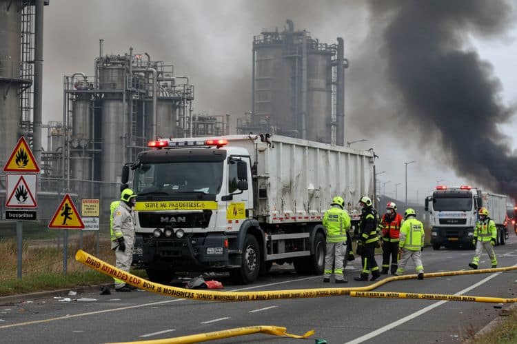 A truck crash scene near a chemical plant, with warning signs for hazardous materials